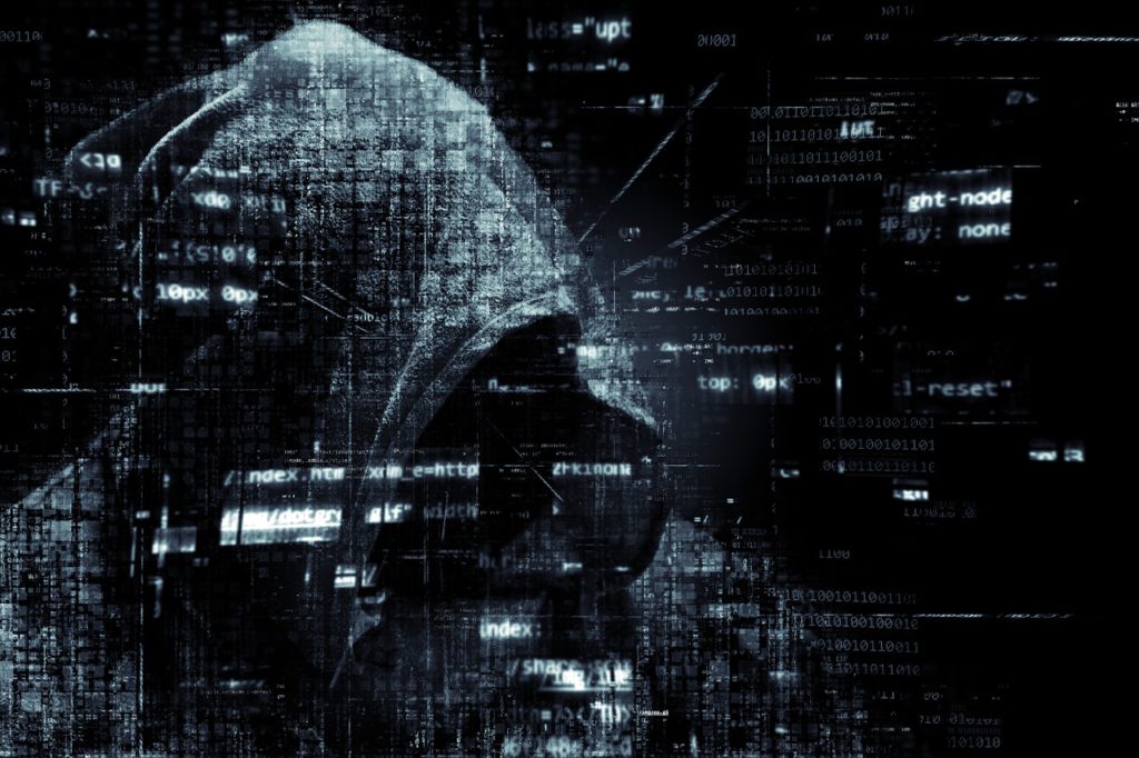 Image of a hooded figure on a black background with lines of computer code floating around them. Scam calls and why they're dangerous. 
