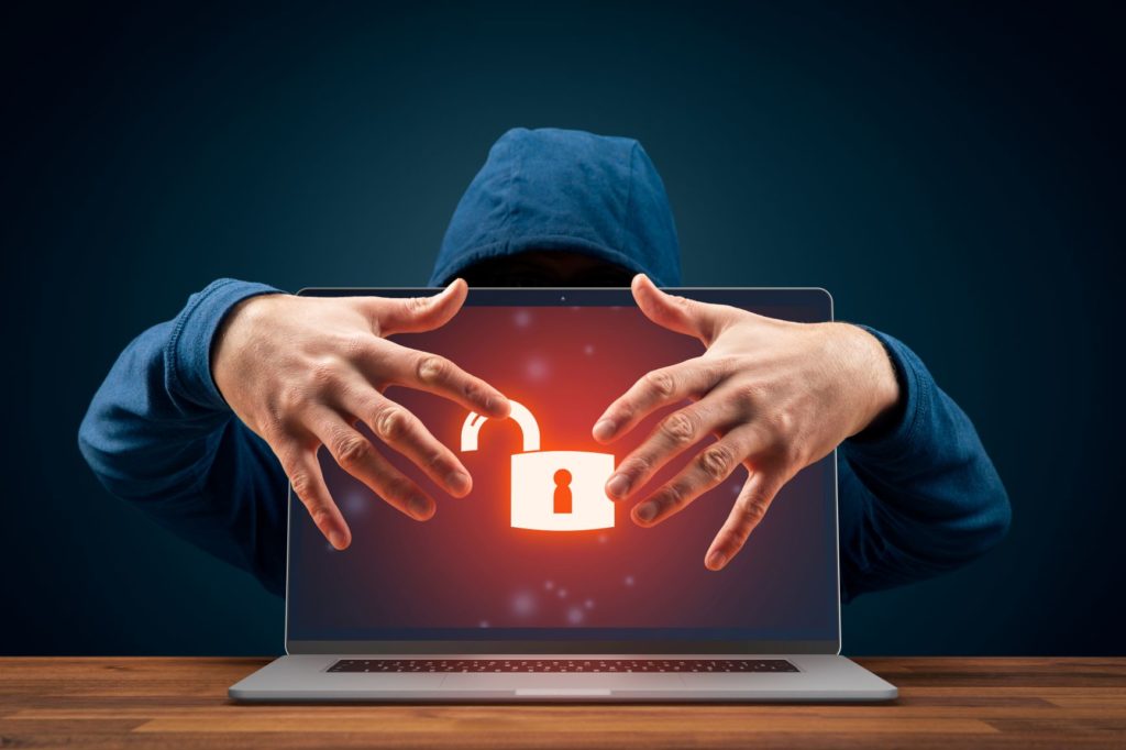 A man in a hoodie reaches around the back of a laptop screen. The screen has a large red padlock icon on it, made to look as though it is unlocked. An insecure password leaves you vulnerable. 